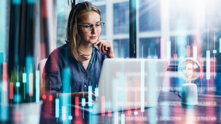 Woman looking at her laptop with graph lines across the image