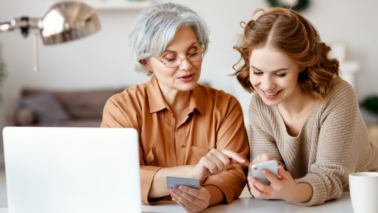 Two women discussing calculations in front of a laptop.