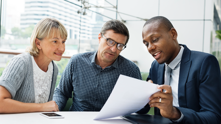 Happy couple reviewing documents with a businessperson.
