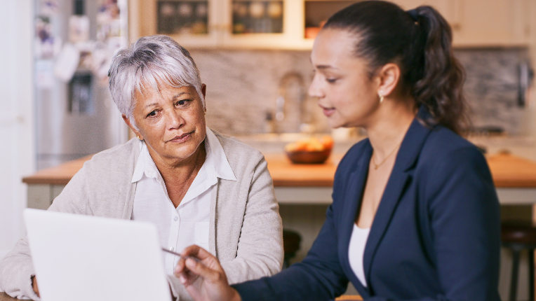 Shot of a senior woman using a laptop during a meeting with a consultant at home.