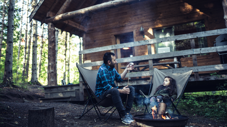 Father and daughter cooking marshmallows on campfire.