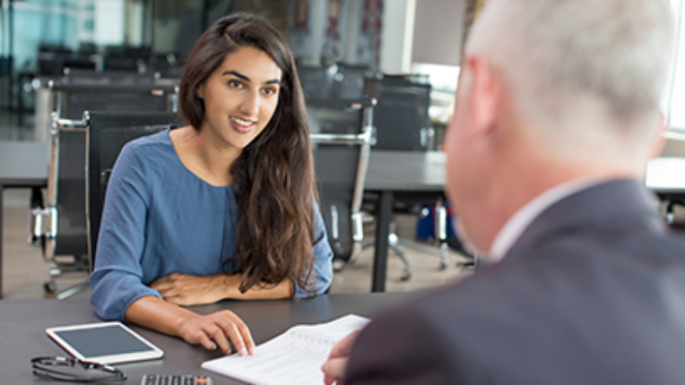 A women having a conversation about market beat report with a man in an office environment