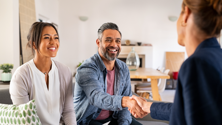Multiethnic couple handshake with consultant at home.