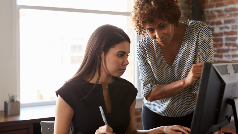 Two Businesswomen Working On Computer In Office.
