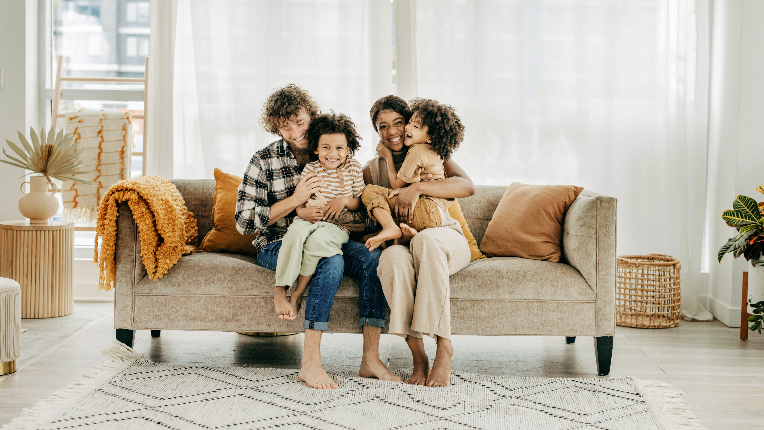 Two parents and two kids sitting on sofa.