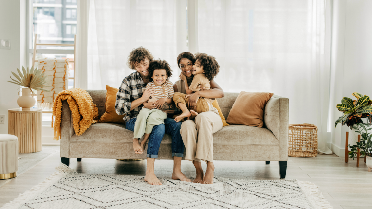 Two parents and two kids sitting on sofa.