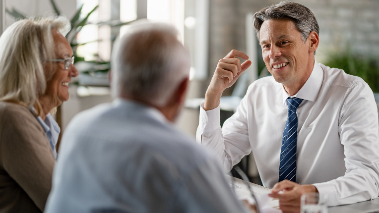 Happy financial advisor having consultations with senior couple in the office.