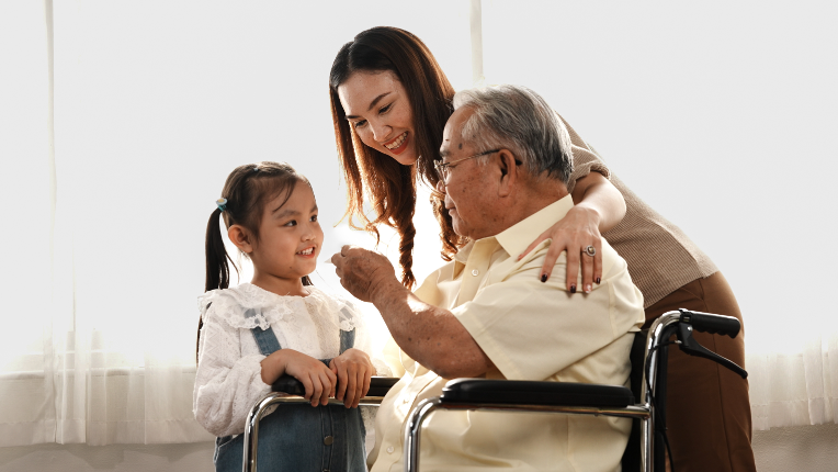 Multi-generation mother and daughter taking care of the senior grandfather in the house.