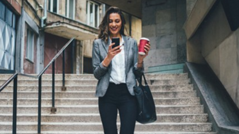 A woman walking down stairs while looking at her cellphone.