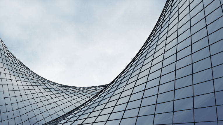 Curved building windows in front of clear blue sky.