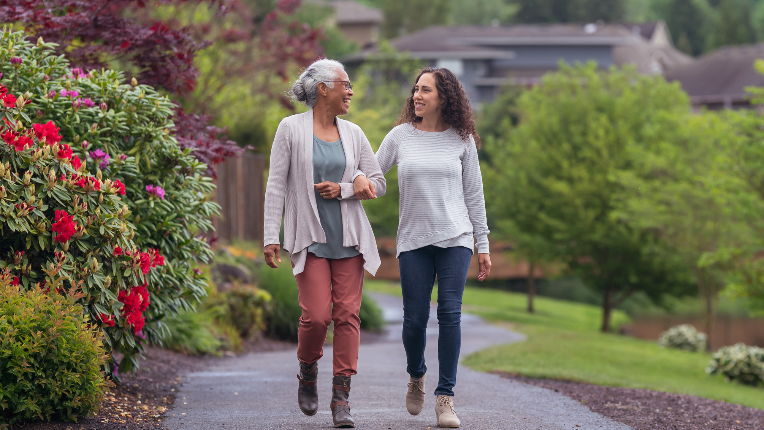 Mother walking down path with daughter surrounded by trees and rose bushes