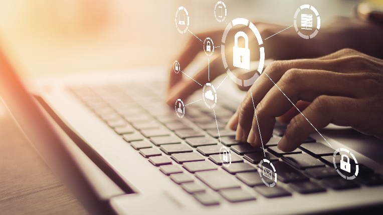 Cropped image of person’s hands typing on laptop keyboard with digital icons, including locks, in front.