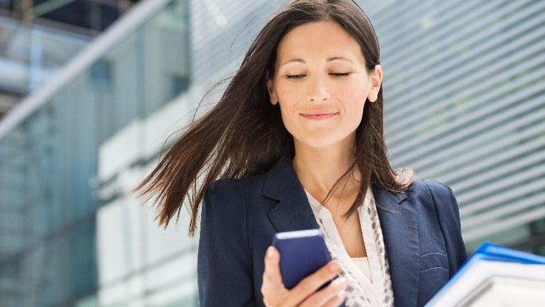 Woman in suit looking at news on her cell phone.