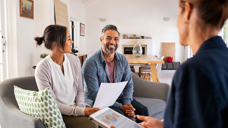 Middle aged couple talking with a financial advisor in their living room