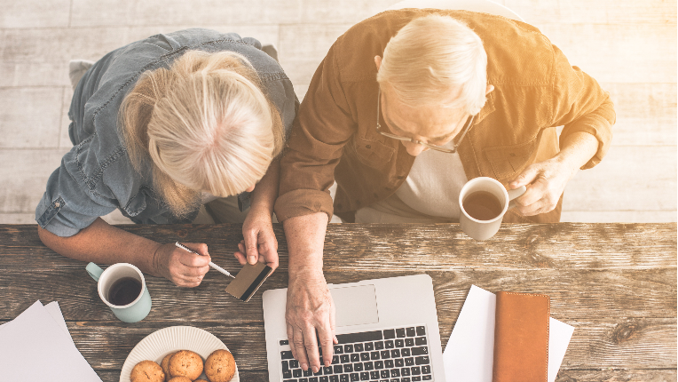Senior man typing on laptop and woman holding credit card