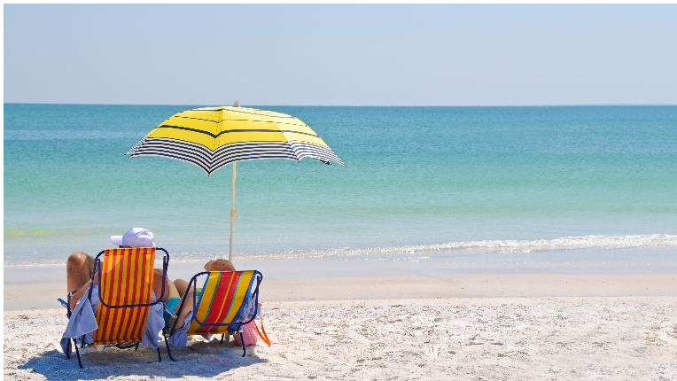 Man, woman on beach under umbrella