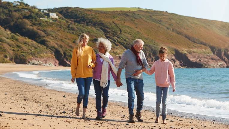 Multi-Generation Family Walking Along Shore On Winter Beach Vacation